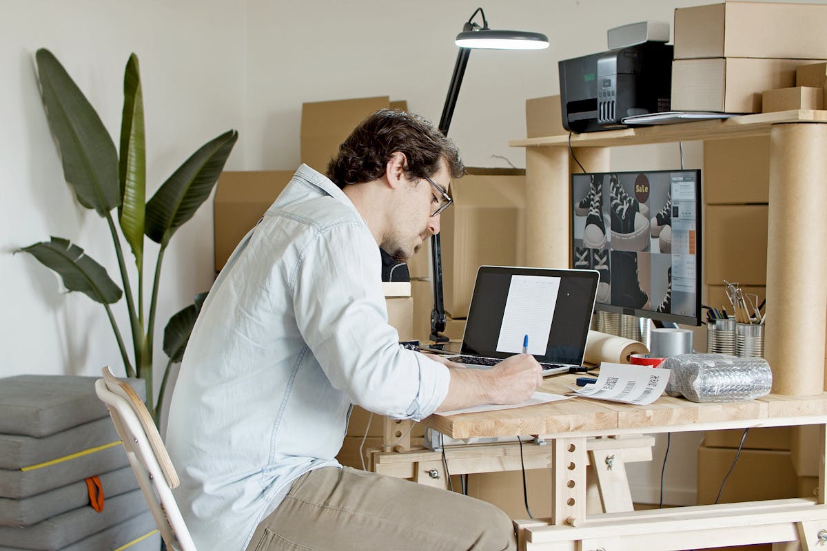 Hispana emprendedora trabajando en su negocio desde casa con laptop y cuaderno