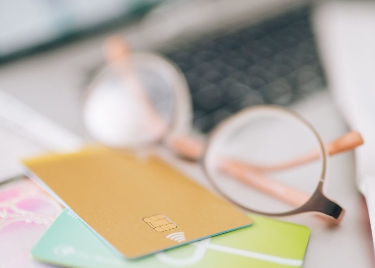 Emprendedor hispano revisando su crédito para negocios con tarjeta y laptop