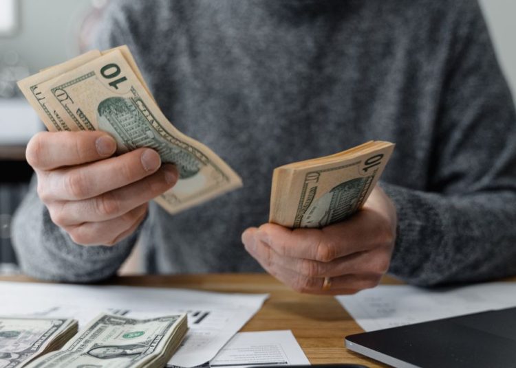 Emprendedor contando dólares de un préstamo para negocios con ITIN