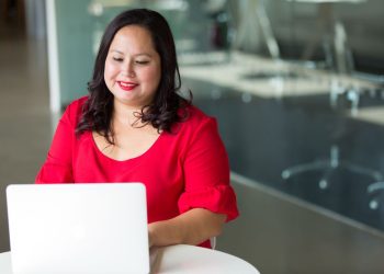 Emprendedora latina sonríe frente a su laptop mientras vende en Amazon con ITIN sin Seguro Social