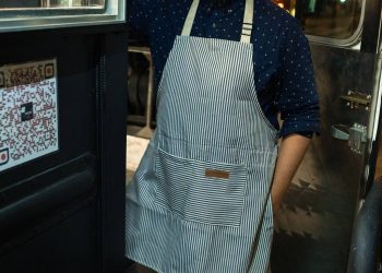 Dueño latino de un food truck con delantal, antes de pagarle a su proveedor y pedirle el formulario W-9