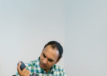 Dueño de negocio latino al teléfono revisando papeles del IRS y el Formulario 8822-B