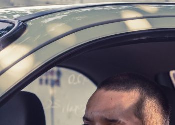 Emprendedor latino manejando su auto de trabajo, deducción con la tarifa por milla del IRS
