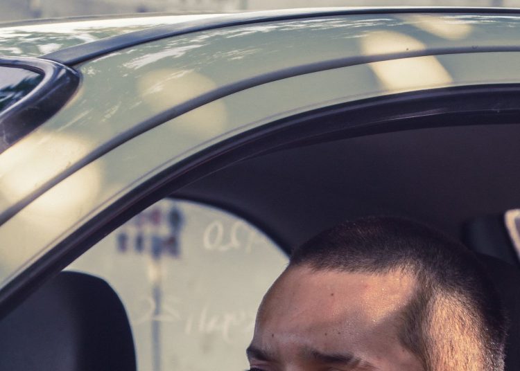 Emprendedor latino manejando su auto de trabajo, deducción con la tarifa por milla del IRS
