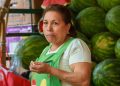 Vendedora latina en su puesto de sandías revisando cuentas — Formulario 843 para recuperar una multa del IRS