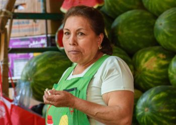 Vendedora latina en su puesto de sandías revisando cuentas — Formulario 843 para recuperar una multa del IRS