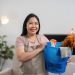 Smiling cleaner holding a bucket of cleaning supplies in a bright home — starting a cleaning business with no money