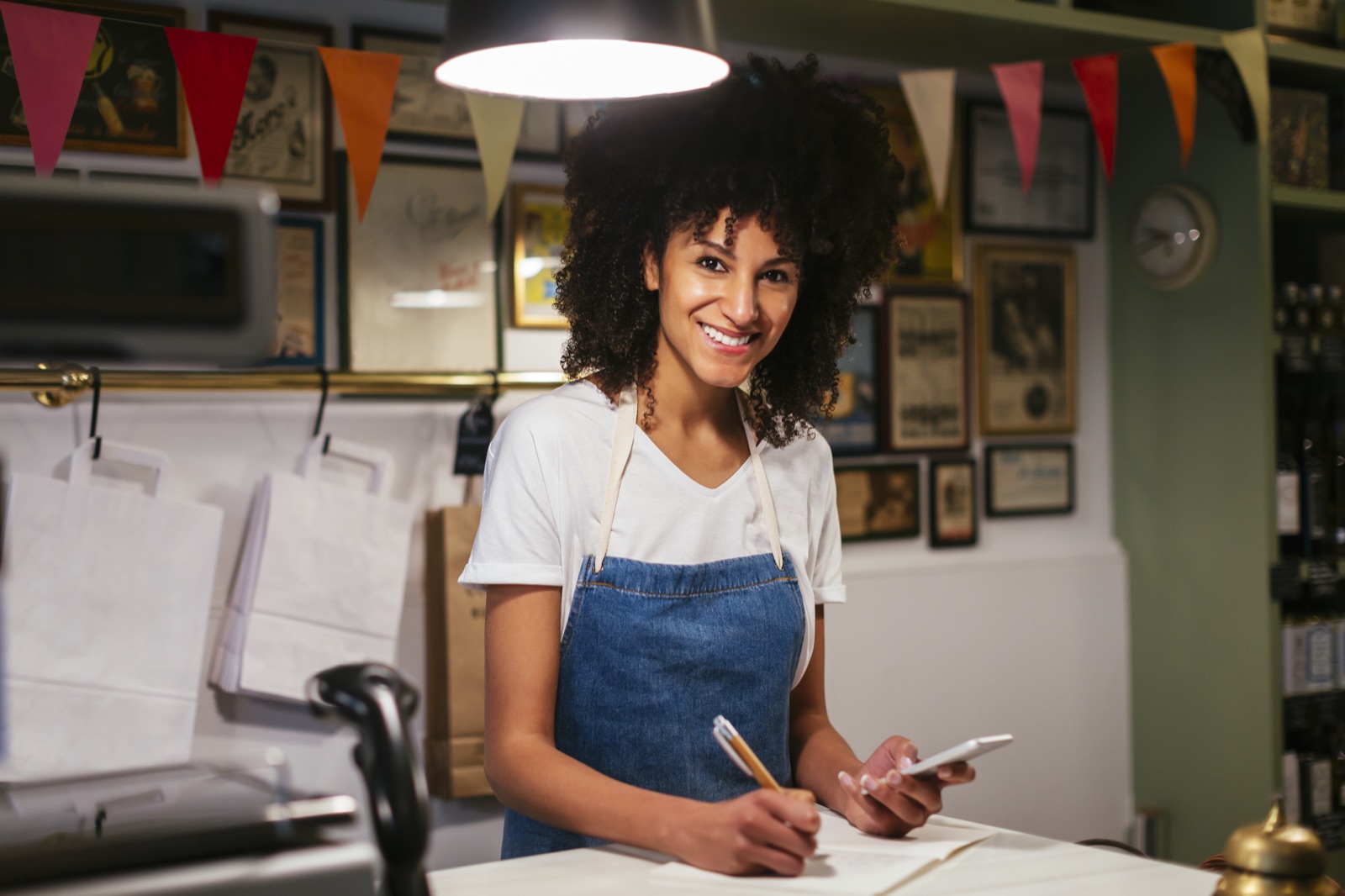 Smiling small business owner taking notes at the counter of her shop