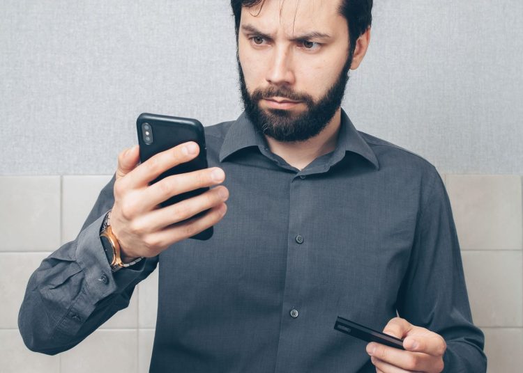 Hombre dueño de negocio revisando un mensaje de la estafa del BOI en el teléfono
