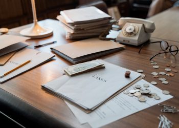 Office desk with tax documents, coins and glasses