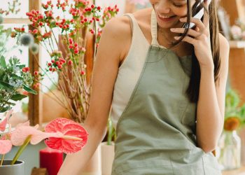 dueña de negocio hispana respondiendo una reseña de un cliente desde su celular en su tienda