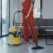 Professional cleaner in red coveralls vacuuming a living room